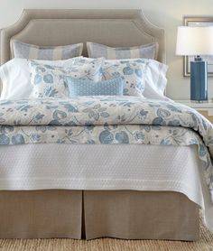 a bed with blue and white comforters in a bedroom next to a lamp on a nightstand