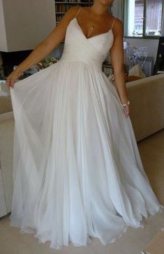 a woman in a white dress standing next to a couch