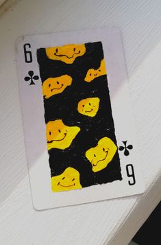 a playing card with yellow and black faces on it's side, in front of a white background