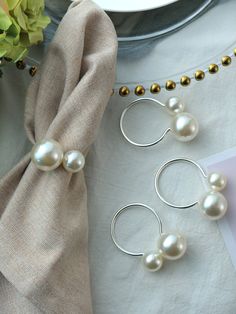 three pieces of jewelry sitting on top of a table next to a plate and flowers