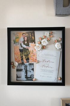 a couple's wedding photos are displayed in a frame on the wall next to flowers