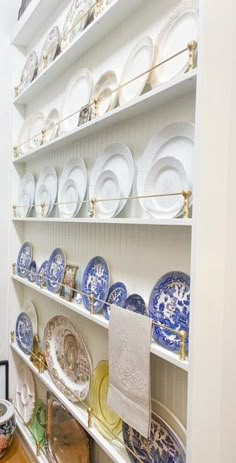 the shelves are full of plates and dishes on them, all in blue and white