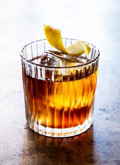 a close up of a drink in a glass with ice and lemon wedges on the rim