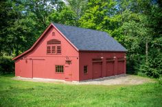 a red barn sits in the middle of some trees