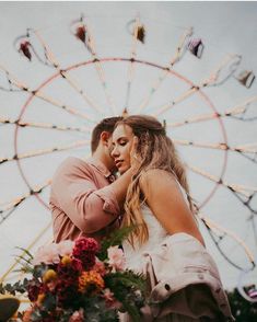 a man and woman standing next to each other in front of a ferris wheel