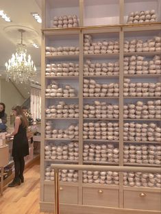 two women standing in front of a large display case filled with white balls and vases