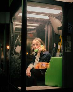 a woman sitting on a bus talking on a phone while holding a green object in her hand