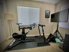 there is a bike and exercise equipment in the room with blinds on the windowsill