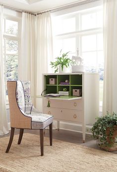 a chair sitting in front of a window next to a desk with a plant on it