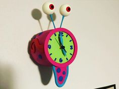 a clock that is on the wall with two eyes and one eyeball attached to it