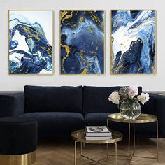 three paintings hang on the wall above a black couch in a living room with gold accents