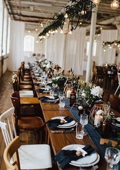 a long table set with place settings and flowers on it for an elegant wedding reception