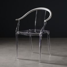 a clear plastic chair sitting on top of a cement floor next to a black wall