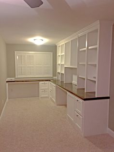 an empty room with white cabinets and black counter tops in the middle of the room