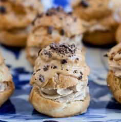 some cookies with frosting and chocolate chips on top are sitting on a blue and white plate