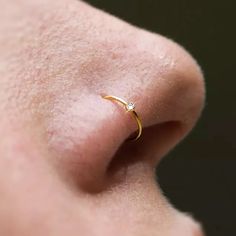 a close up of a person's nose with a small diamond ring on it