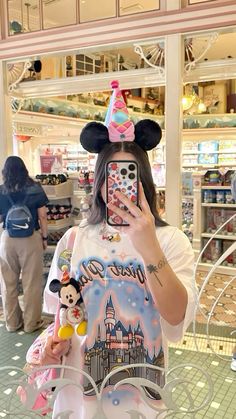 a woman taking a selfie with her cell phone in front of mickey mouse ears