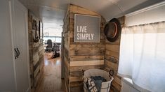 the inside of an rv is decorated with wood planks and white walls, along with a sign that says live simply