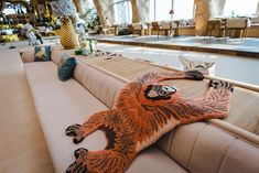 a stuffed animal sitting on the back of a couch in a room filled with tables and chairs