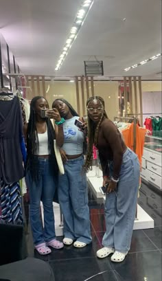 three women standing in front of a clothing rack