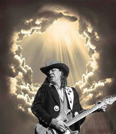 a man in a cowboy hat is playing an electric guitar and clouds are behind him