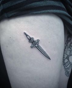 a black and white photo of a knife tattoo on the side of a woman's thigh