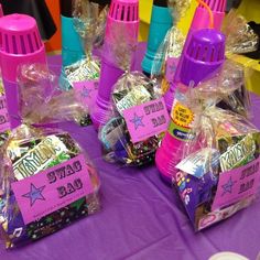 purple and blue plastic cups with candy wrapped in cellophane on a purple table cloth