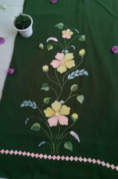 a green table cloth with flowers painted on it