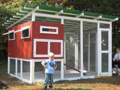 a little boy standing in front of a chicken coop