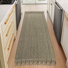 a kitchen with an area rug on the floor next to the stove and dishwasher