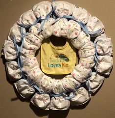 a baby's bib hanging on the wall next to a wreath made out of diapers