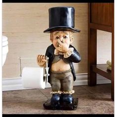 a statue of an old man with a top hat and holding a roll of toilet paper