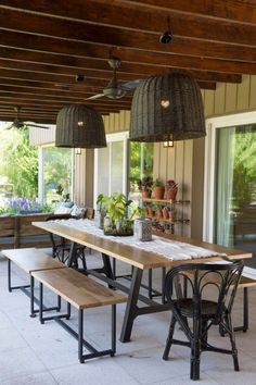 an outdoor dining area with wooden benches and potted plants hanging from the rafters