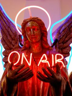 a neon sign that says on air with an angel holding the word in front of it