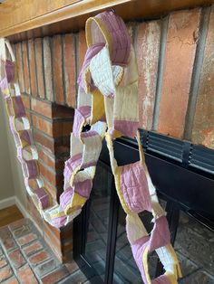 a pink and yellow scarf hanging from a fireplace mantle next to a brick fire place