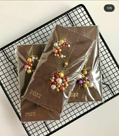 three pieces of chocolate covered in beads on a cooling rack with a black wire tray