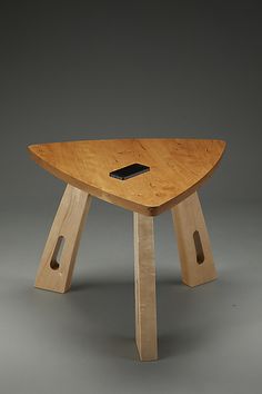 a wooden table with a cell phone on it's top and two holes in the middle