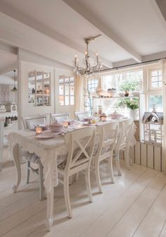 a dining room table with white chairs and a chandelier