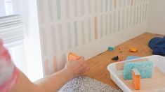 a woman is painting the walls in her room with pastel paint and other things on the floor