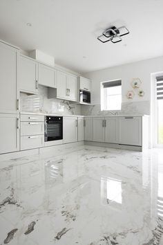 an empty kitchen with white cabinets and marble flooring is pictured in this image from the front view