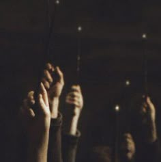 several people holding up their hands in the air with lights shining on them and one person raising his hand