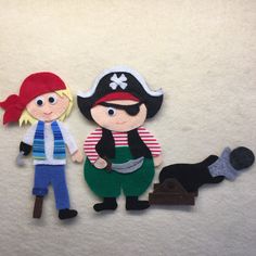 two felt pirate dolls standing next to each other on a white surface with a black dog