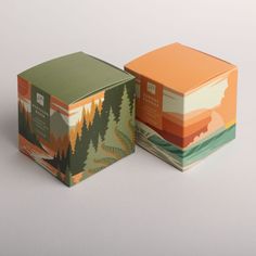 two boxes that are sitting side by side on a white surface with trees and mountains in the background