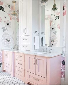 a bathroom with pink cabinets and floral wallpaper