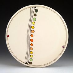 a white plate with multicolored designs on the front and back sides, sitting on a gray surface