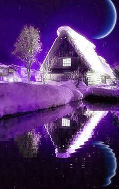 a house with a thatched roof is reflected in the still water at night time