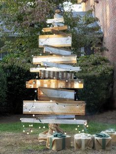 a christmas tree made out of wooden planks and wrapped in string lights is shown