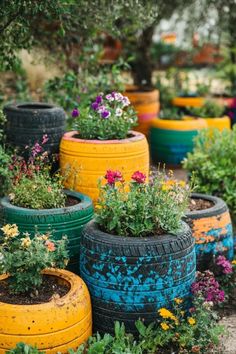 many colorful tires are lined up together in the garden with flowers growing out of them