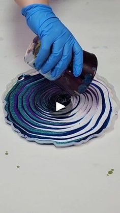 a person in blue gloves and rubber gloves is painting a circular design on the floor