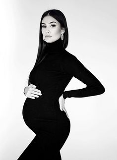 a pregnant woman posing for a black and white photo with her hands on her hips